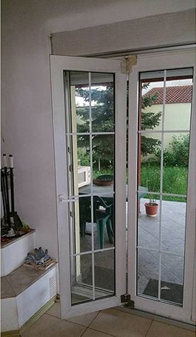 Ușă armonică din PVC albă, cu foile deschise spre terasă.