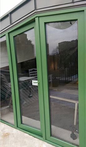 Ușa dublă cu tocul verde, spre terasa restaurantului.