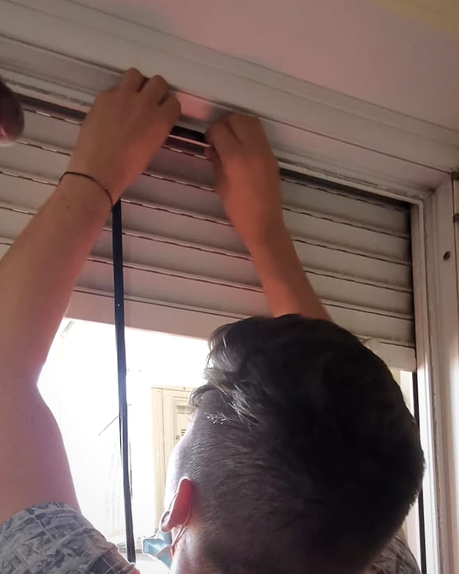 Tehnician care montează o garnitură nouă pe tocul unei uși.